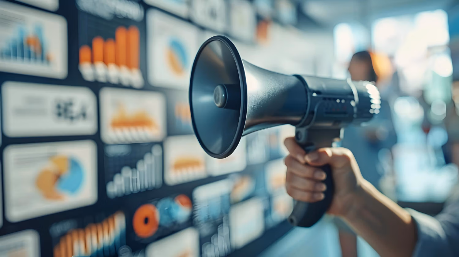 Hand holding a megaphone in front of a wall of digital screens